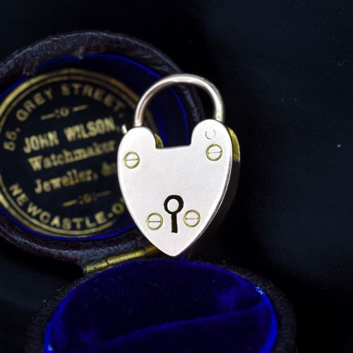 fig 1. An antique 9ct gold heart-shaped padlock pendant with a smooth polished finish, central keyhole detail, and visible screw head accents.