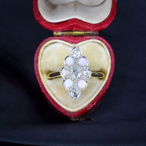 fig 2. An Edwardian 18ct gold and platinum navette cluster ring featuring a central old cut diamond bordered by four cabochon opals and additional diamond accents.