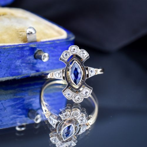 fig 3. An Art Deco gold ring featuring a central marquise-cut blue sapphire framed by an intricate openwork diamond-set navette halo.