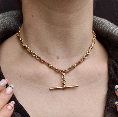 fig 1. A 9ct yellow gold double Albert chain necklace with love knot links and a central T-bar drop displayed on a black bust.