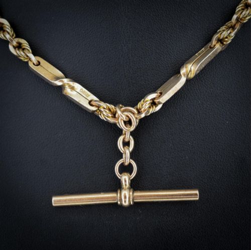 fig 3. A 9ct yellow gold double Albert chain necklace with love knot links and a central T-bar drop displayed on a black bust.