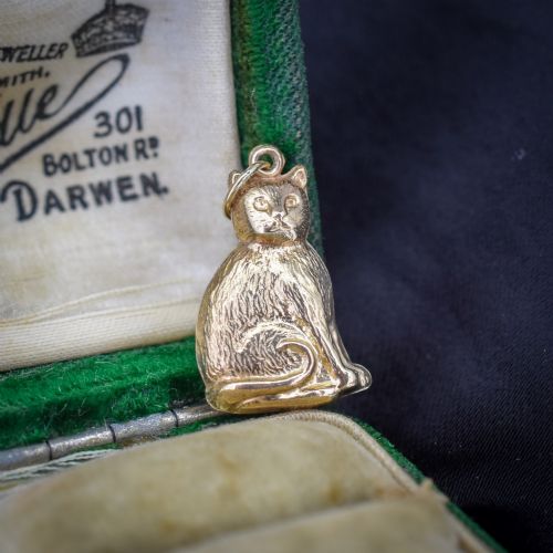 fig 1. A small 9ct yellow gold charm shaped as a seated cat with engraved fur texture and a loop at the top for suspension.