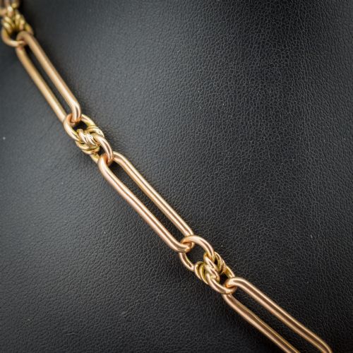 fig 2. An antique 9ct yellow gold necklace featuring elongated trombone links, twisted love knots, and a central suspended T-bar.