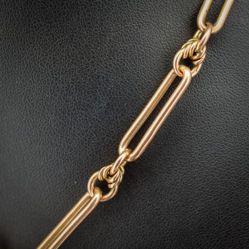 fig 3. An antique 9ct yellow gold necklace featuring elongated trombone links, twisted love knots, and a central suspended T-bar.