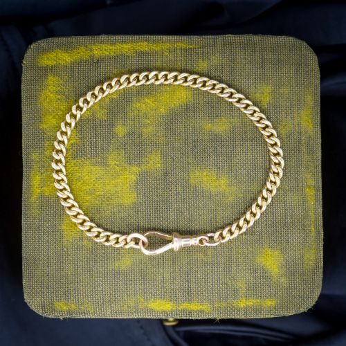 fig 1. An antique 9ct yellow gold uniform curb link chain bracelet with a dog clip clasp arrangement resting on a textured olive display pad.
