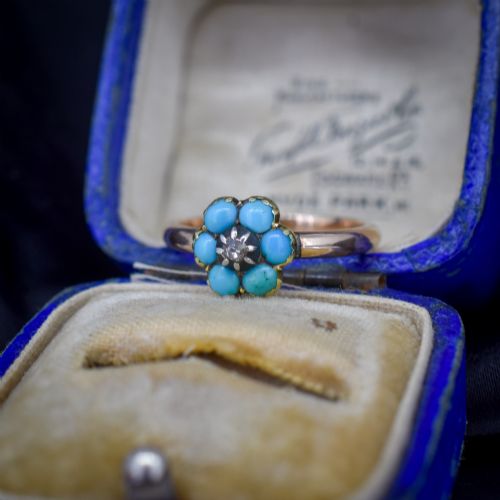 fig 2. An antique 15ct yellow gold ring featuring a central diamond surrounded by six turquoise cabochons forming a floral cluster.