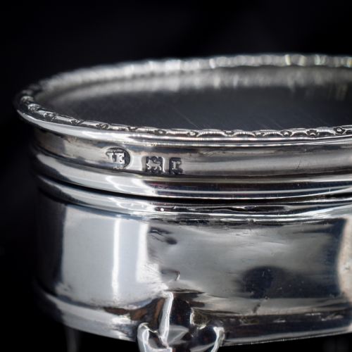 fig 1. An oval silver trinket box resting on three cabriole legs with a patterned rim along the lid.