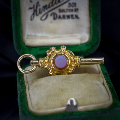 fig 1. An antique gold watch key pendant featuring scrollwork ornamentation around a central dark green bloodstone seal, topped with a suspension ring.