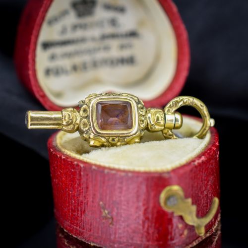 fig 2. An antique gold-cased pocket watch key pendant inset with a square red agate stone and decorated with intricate chased patterns.