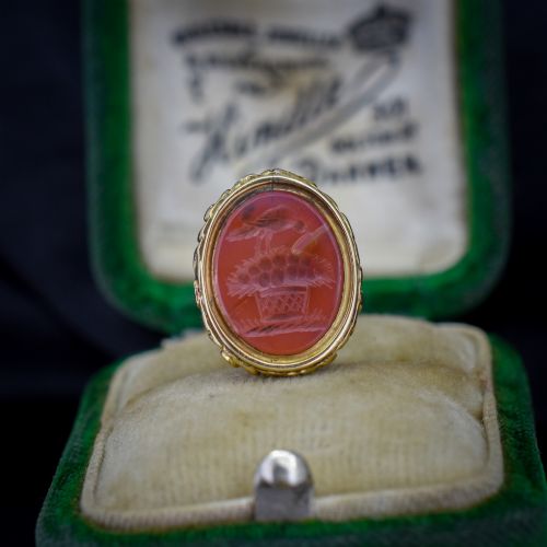 fig 1. An oval orange-red carnelian gem carved with an intaglio mother bird motif, set within a chased gold-cased fob mount.