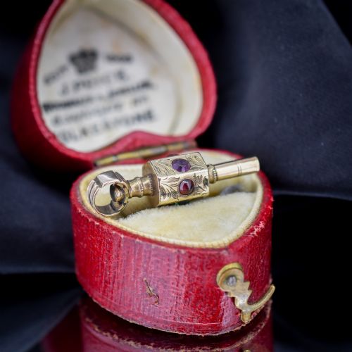 fig 1. An antique yellow gold barrel watch key fob pendant with engraved scrollwork and a vertical setting of acrostic gemstones.