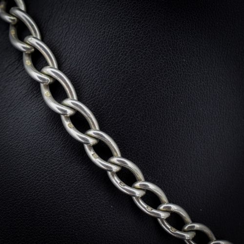 fig 3. An Edwardian sterling silver Albert watch chain featuring heavy oval links, a central T-bar, and a dog clip clasp.
