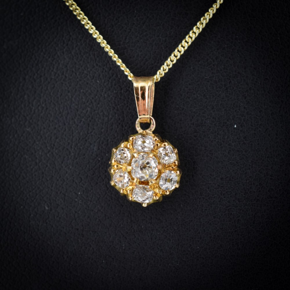 An antique yellow gold necklace featuring a flower cluster pendant set with old cut diamonds suspended on a fine chain.