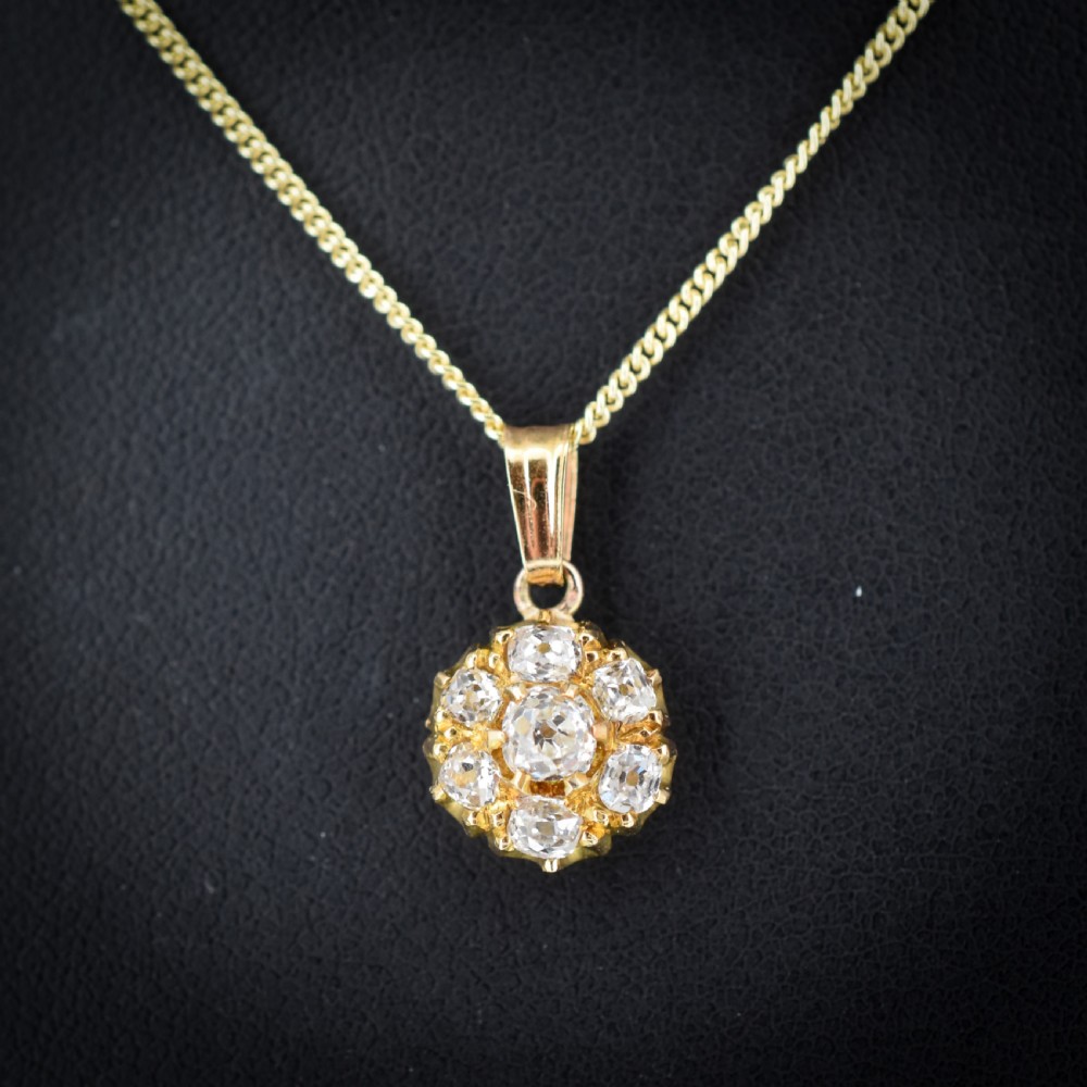 An antique yellow gold necklace featuring a flower cluster pendant set with old cut diamonds suspended on a fine chain. View III