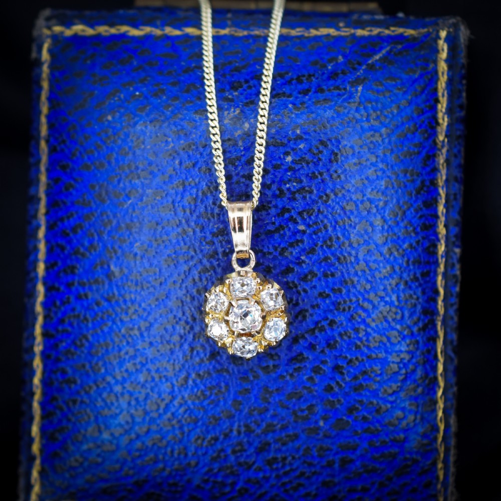 An antique yellow gold necklace featuring a flower cluster pendant set with old cut diamonds suspended on a fine chain. View V