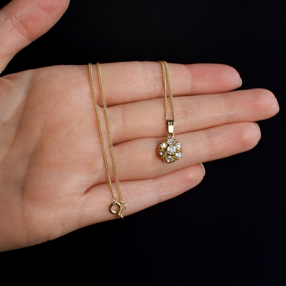 An antique yellow gold necklace featuring a flower cluster pendant set with old cut diamonds suspended on a fine chain. View IX