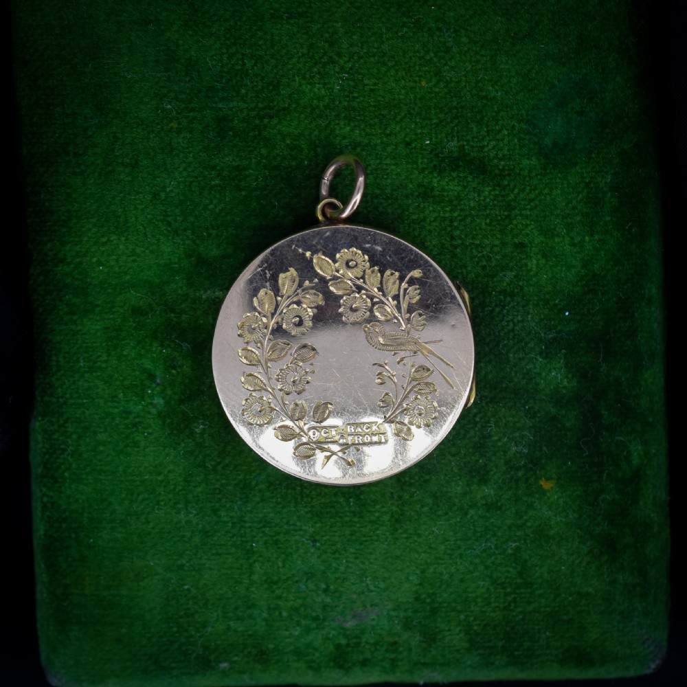 A round 9ct yellow gold locket pendant with hand-engraved swallow, ribbon bow, floral wreath motifs, and monogrammed initials. View II
