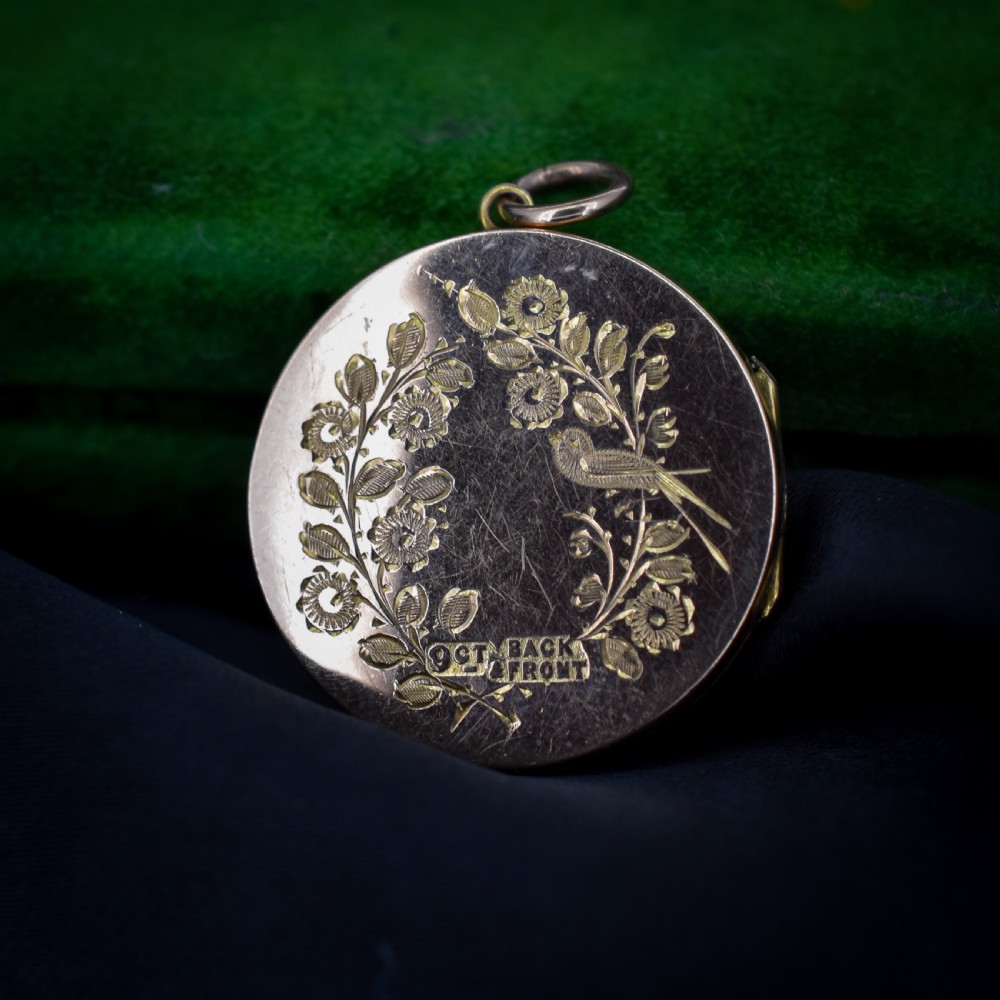 A round 9ct yellow gold locket pendant with hand-engraved swallow, ribbon bow, floral wreath motifs, and monogrammed initials. View III
