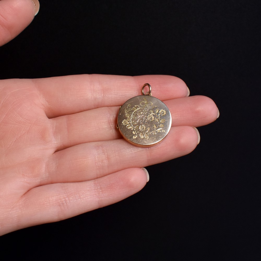 A round 9ct yellow gold locket pendant with hand-engraved swallow, ribbon bow, floral wreath motifs, and monogrammed initials. View IV