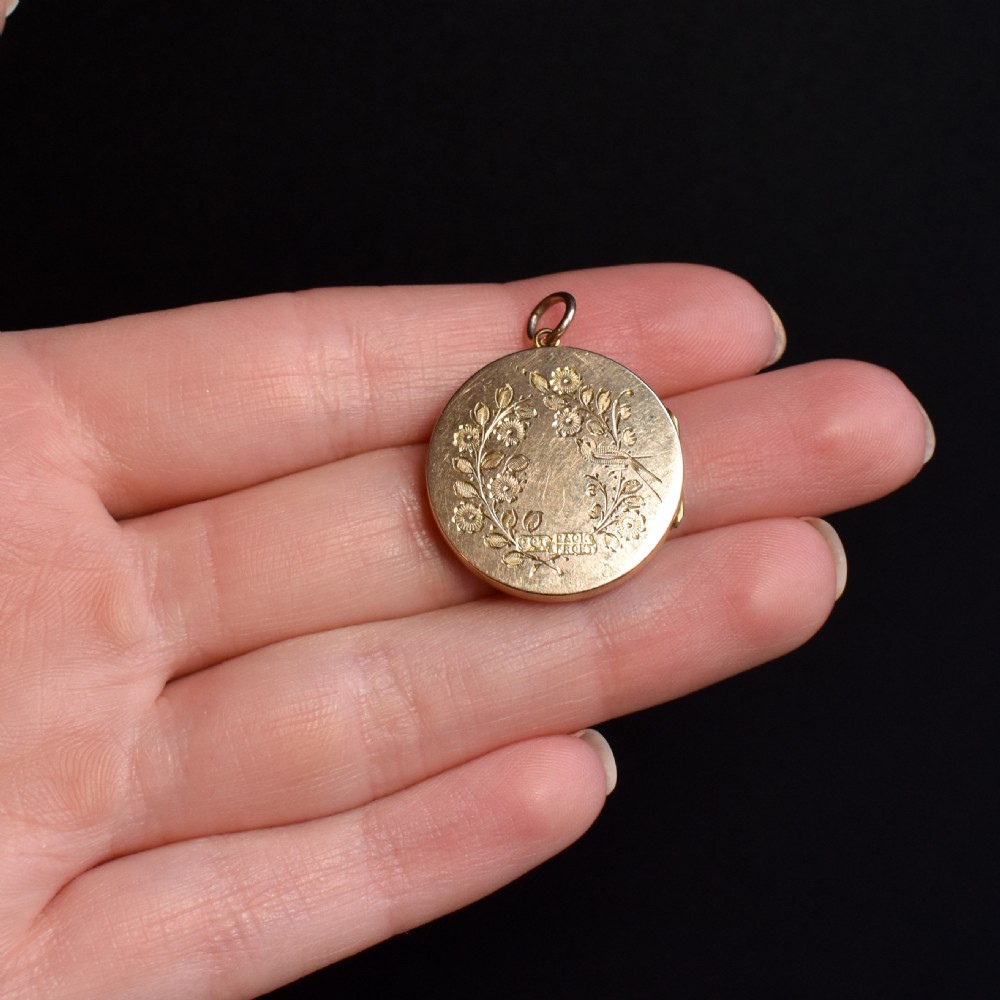A round 9ct yellow gold locket pendant with hand-engraved swallow, ribbon bow, floral wreath motifs, and monogrammed initials. View VII