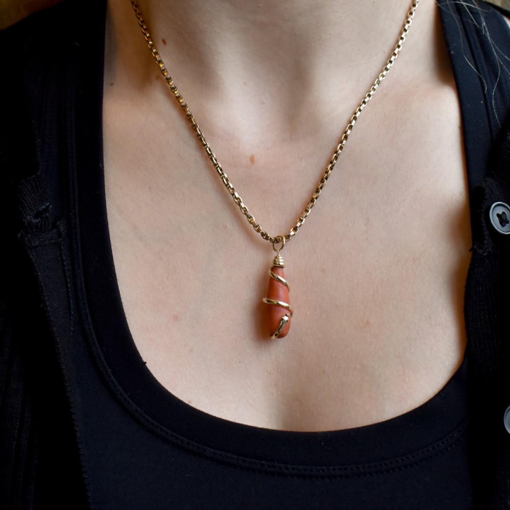 An antique Victorian pendant featuring an orange coral drop wrapped with a coiled 15ct gold snake motif. View VII