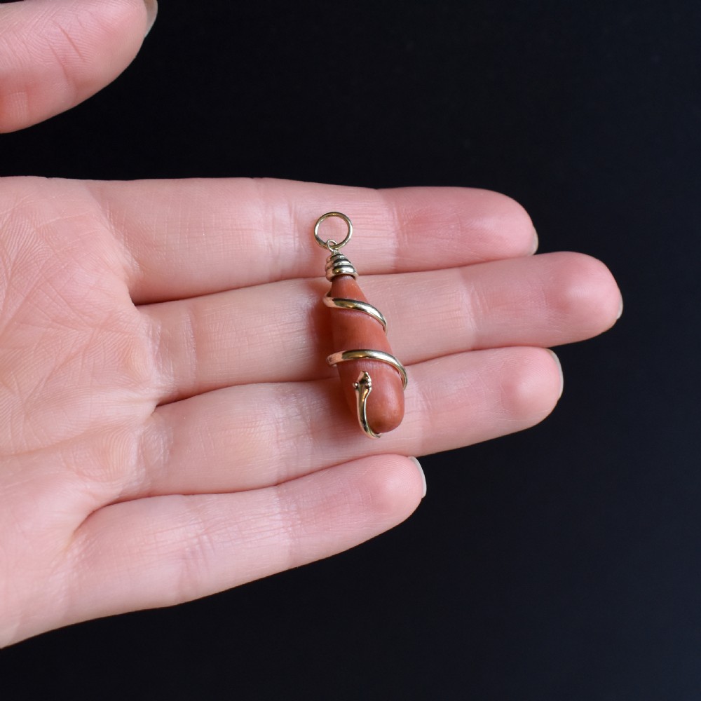 An antique Victorian pendant featuring an orange coral drop wrapped with a coiled 15ct gold snake motif. View VIII