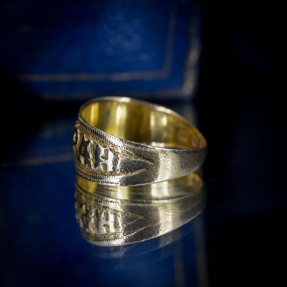 A wide yellow gold band ring featuring raised lettering spelling MIZPAH against a textured background with milled borders. View V