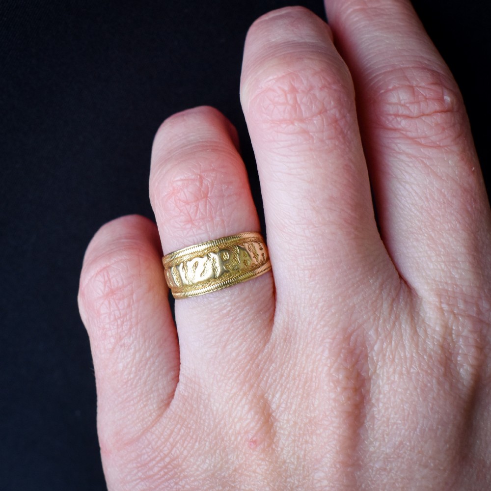 A wide yellow gold band ring featuring raised lettering spelling MIZPAH against a textured background with milled borders. View IX