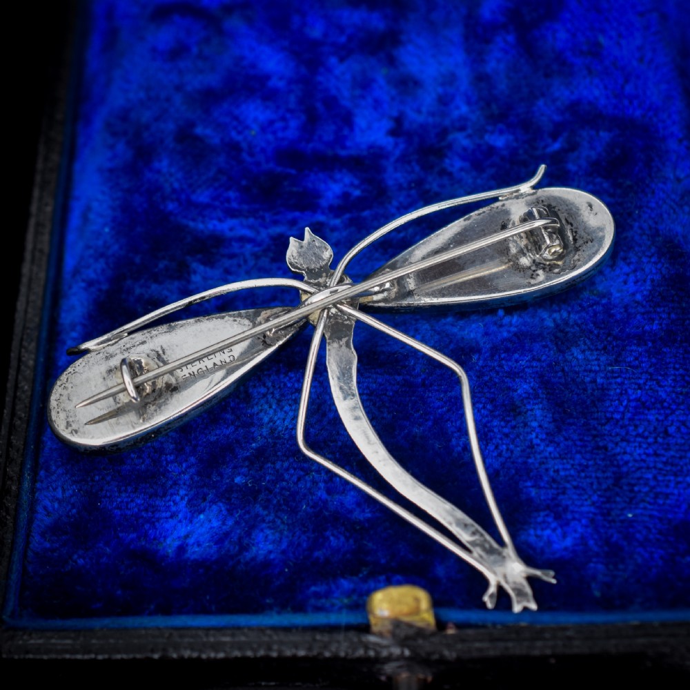 An Art Deco sterling silver brooch designed in the shape of a dragonfly with iridescent blue butterfly wings set beneath glass. View V