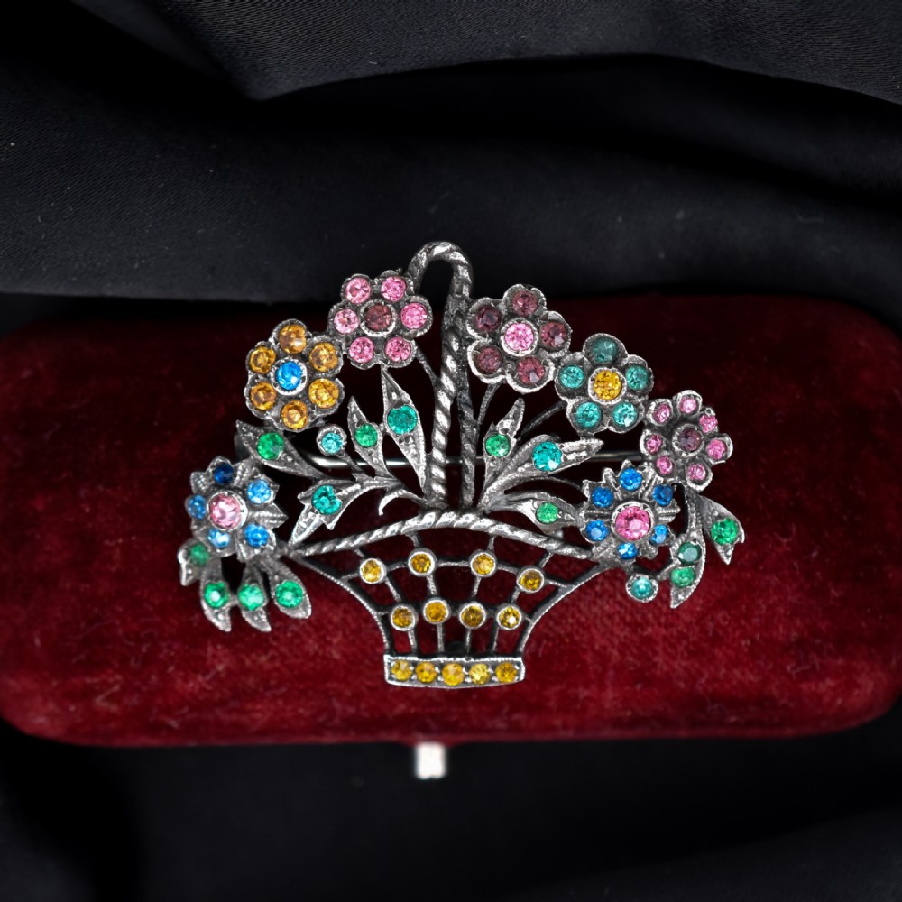 An openwork silver brooch crafted in the shape of a flower basket, set with round multi-coloured paste stones in pink, blue, yellow, and green. View III