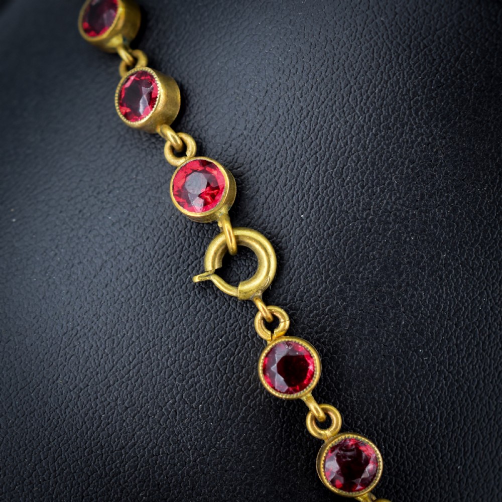 An Edwardian gold gilt riviere necklace featuring round, bezel-set facetted red paste stones connected by fine metal links. View VI