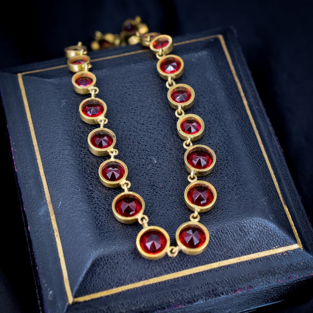 An Edwardian gold gilt riviere necklace featuring round, bezel-set facetted red paste stones connected by fine metal links. View VII