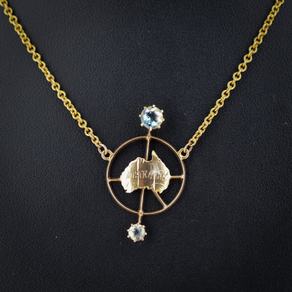 A 15ct yellow gold chain supporting a circular drop pendant featuring an Australian continent map cutout set between two round paste stones.