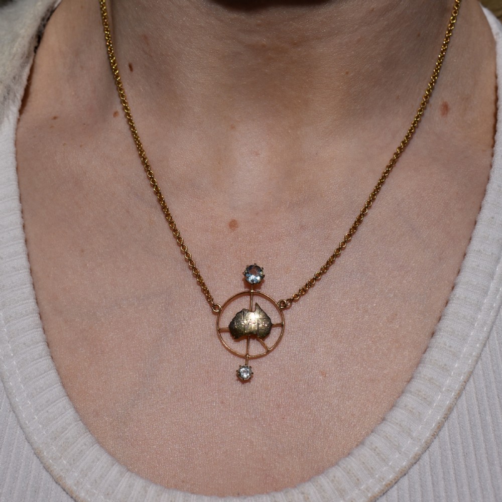 A 15ct yellow gold chain supporting a circular drop pendant featuring an Australian continent map cutout set between two round paste stones. View VIII