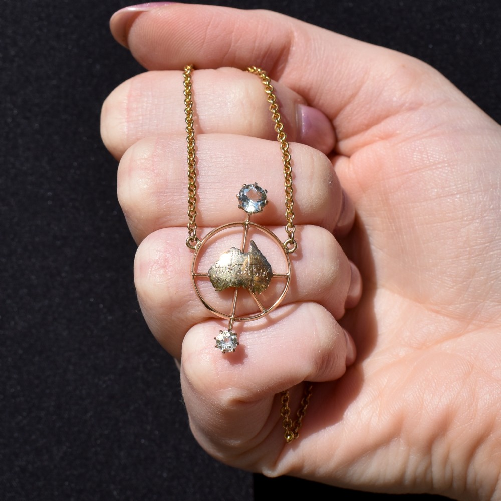 A 15ct yellow gold chain supporting a circular drop pendant featuring an Australian continent map cutout set between two round paste stones. View IX