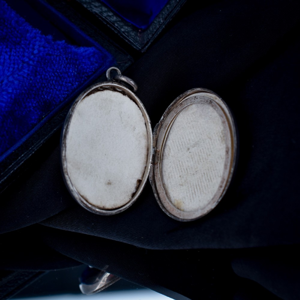An oval antique sterling silver locket decorated with an applied horseshoe motif and hand-engraved leaf patterns. View VIII