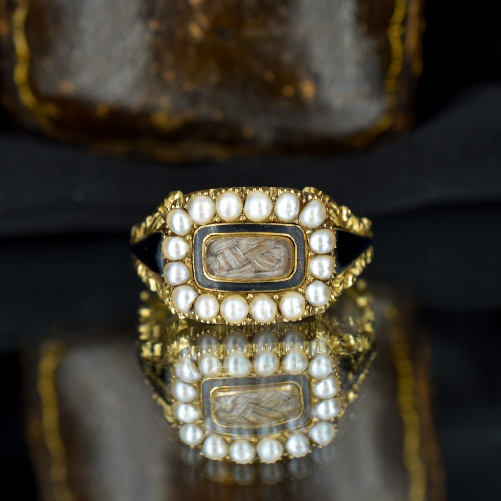 An antique 18ct gold Georgian mourning ring featuring a central woven hair compartment framed by black enamel and a border of seed pearls. View II