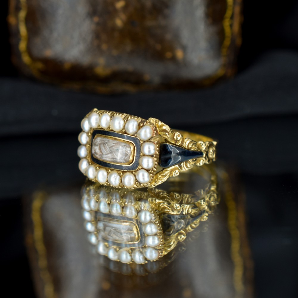 An antique 18ct gold Georgian mourning ring featuring a central woven hair compartment framed by black enamel and a border of seed pearls. View III