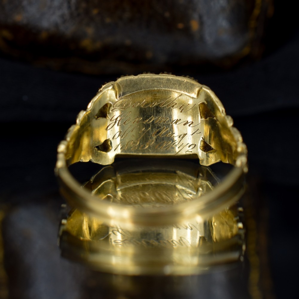 An antique 18ct gold Georgian mourning ring featuring a central woven hair compartment framed by black enamel and a border of seed pearls. View VI
