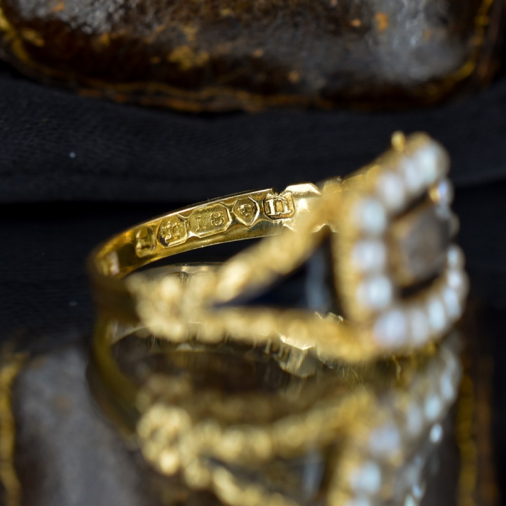 An antique 18ct gold Georgian mourning ring featuring a central woven hair compartment framed by black enamel and a border of seed pearls. View VII