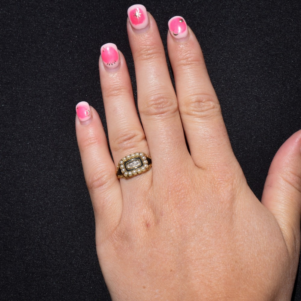 An antique 18ct gold Georgian mourning ring featuring a central woven hair compartment framed by black enamel and a border of seed pearls. View IX