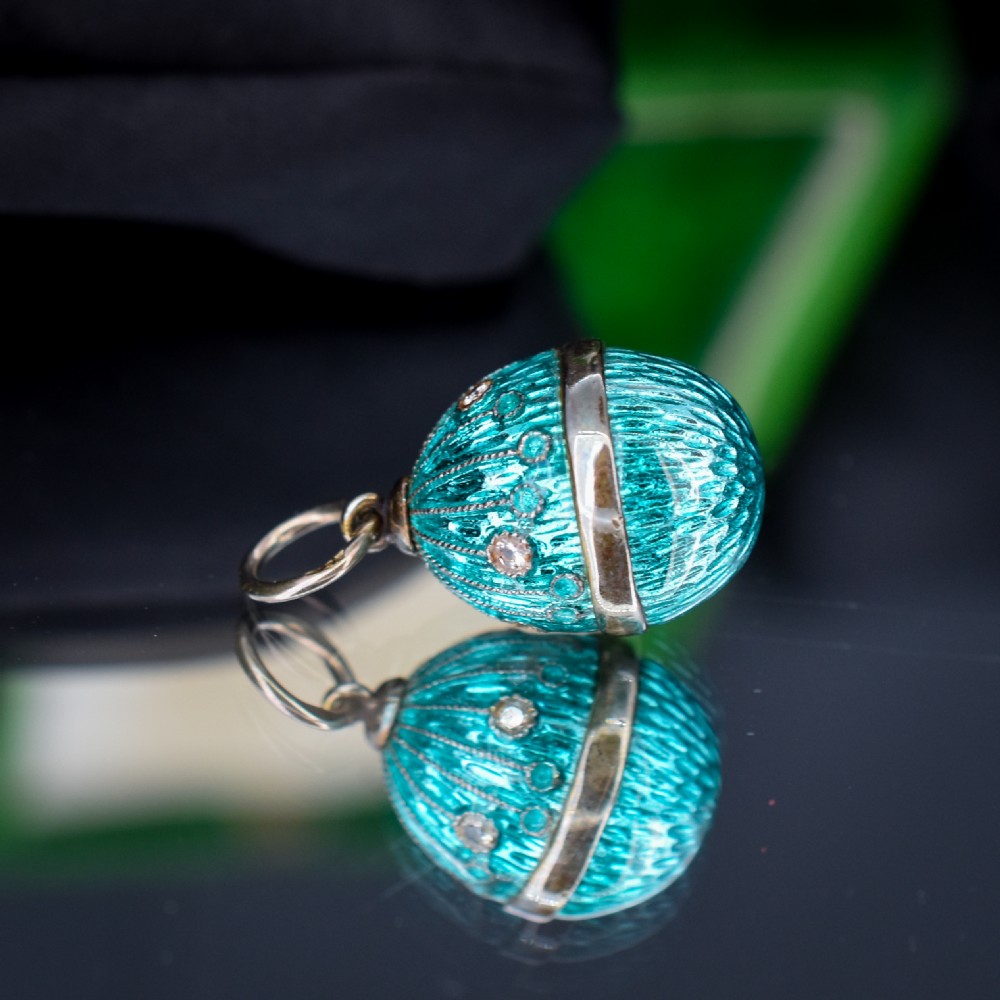 An egg-shaped silver charm pendant featuring vibrant turquoise blue guilloche enamel with fine engine-turned details and double silver mounting rings. View II