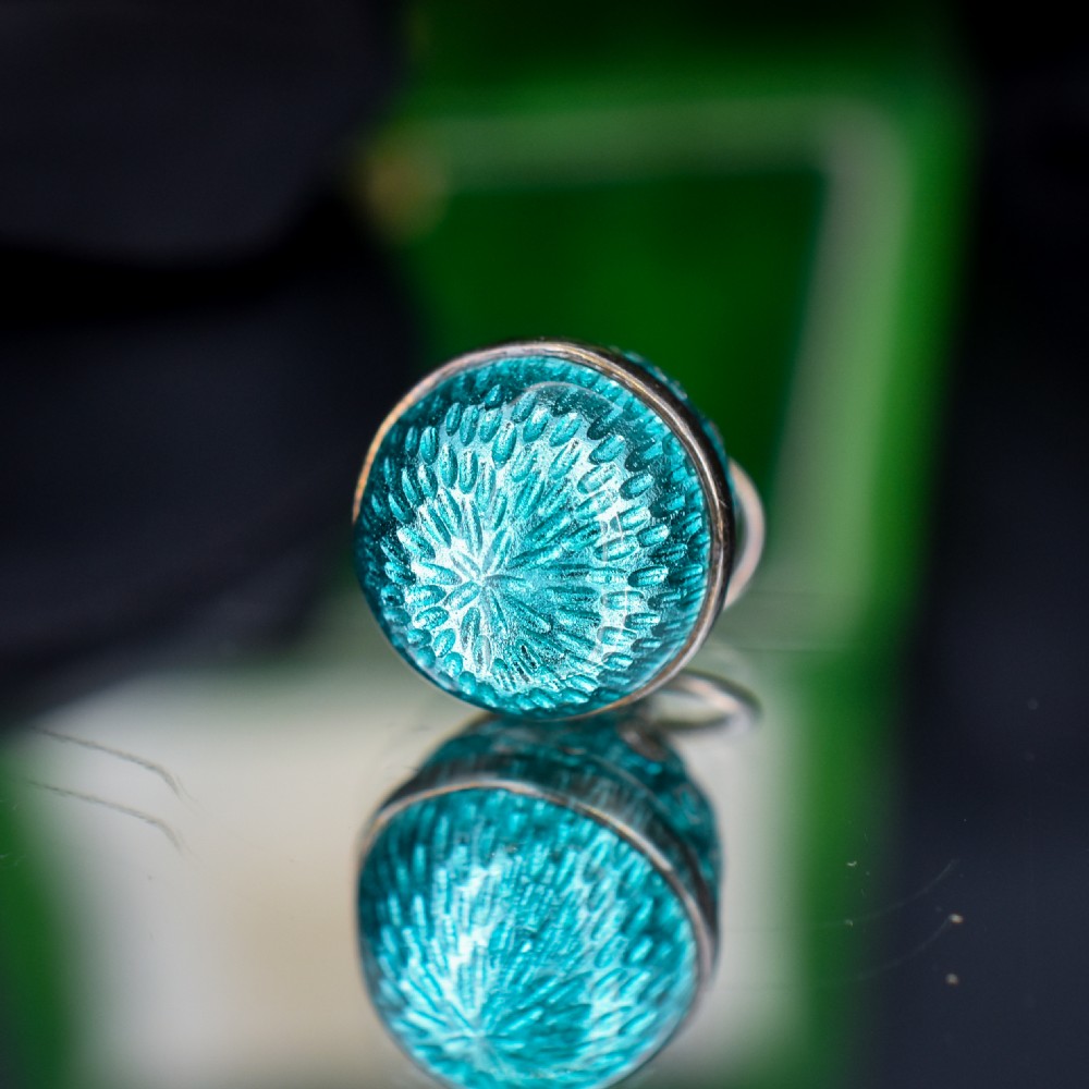 An egg-shaped silver charm pendant featuring vibrant turquoise blue guilloche enamel with fine engine-turned details and double silver mounting rings. View III