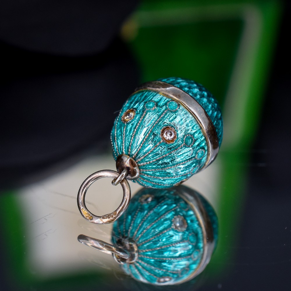 An egg-shaped silver charm pendant featuring vibrant turquoise blue guilloche enamel with fine engine-turned details and double silver mounting rings. View IV