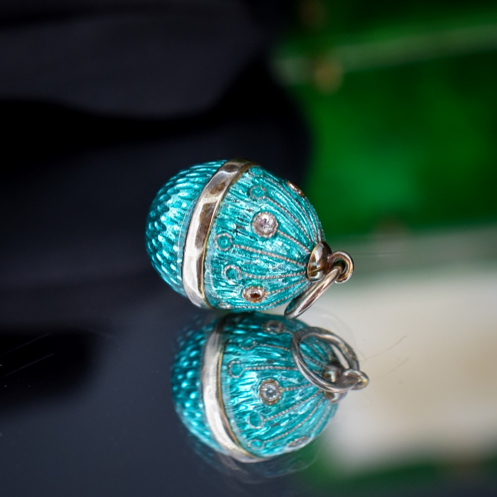 An egg-shaped silver charm pendant featuring vibrant turquoise blue guilloche enamel with fine engine-turned details and double silver mounting rings. View VI
