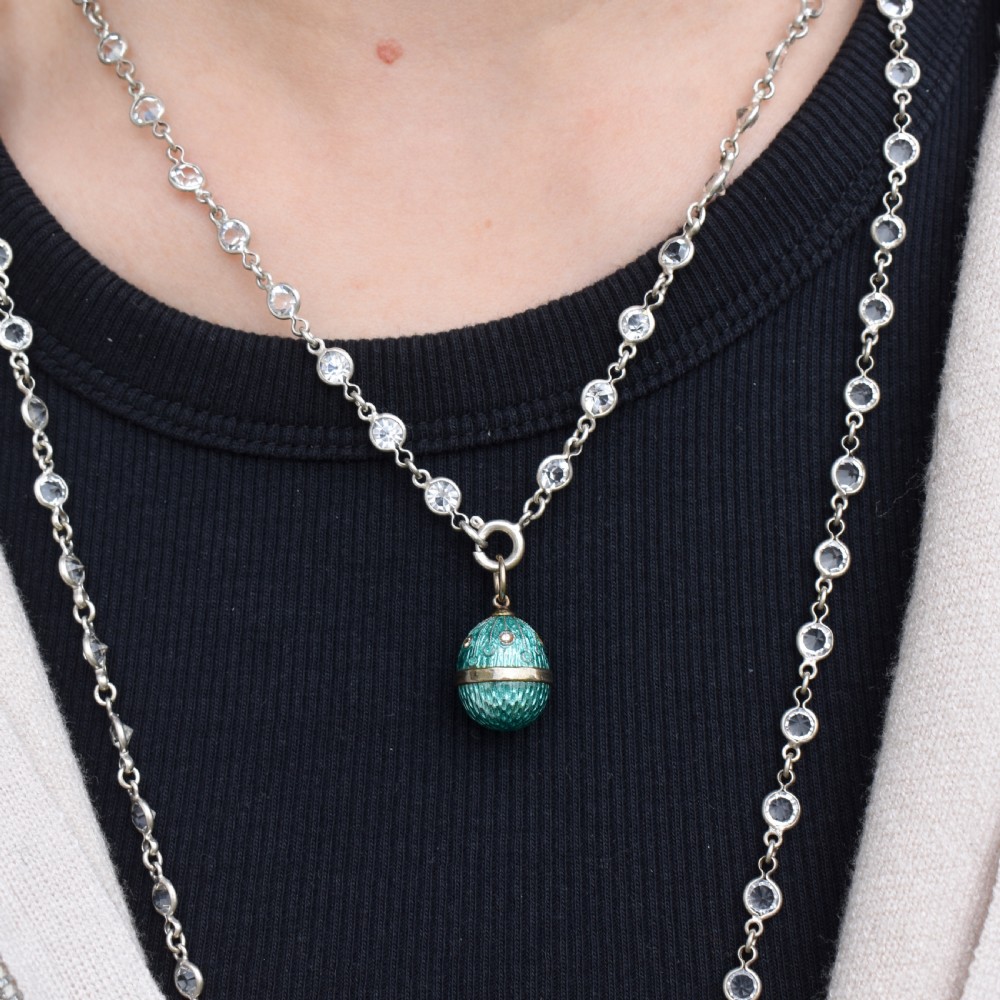 An egg-shaped silver charm pendant featuring vibrant turquoise blue guilloche enamel with fine engine-turned details and double silver mounting rings. View VII