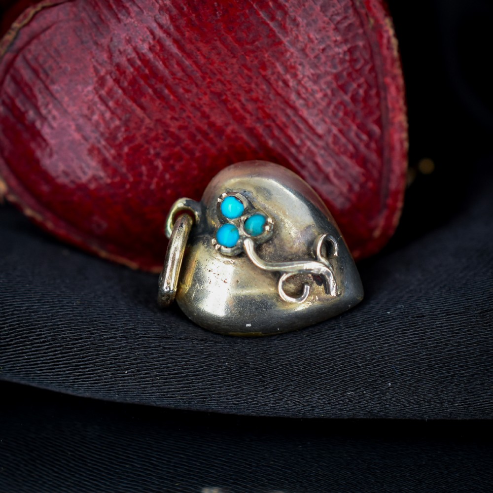 A heart-shaped gold pendant decorated with a raised stem motif set with three round blue turquoise cabochons in a floral pattern. View III