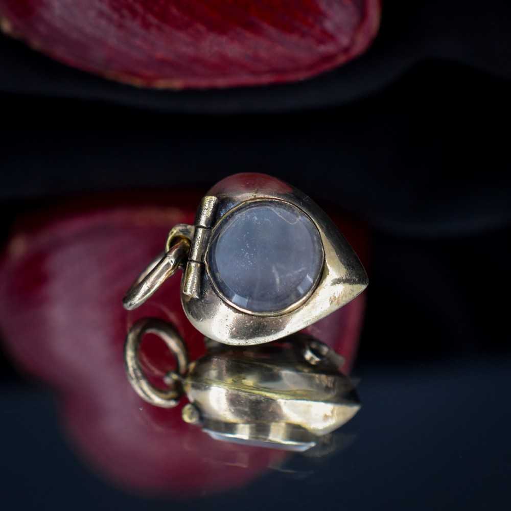 A heart-shaped gold pendant decorated with a raised stem motif set with three round blue turquoise cabochons in a floral pattern. View IV