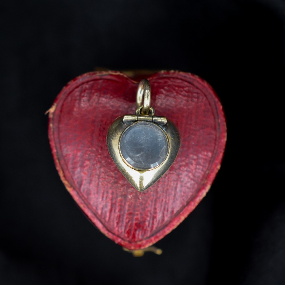 A heart-shaped gold pendant decorated with a raised stem motif set with three round blue turquoise cabochons in a floral pattern. View V