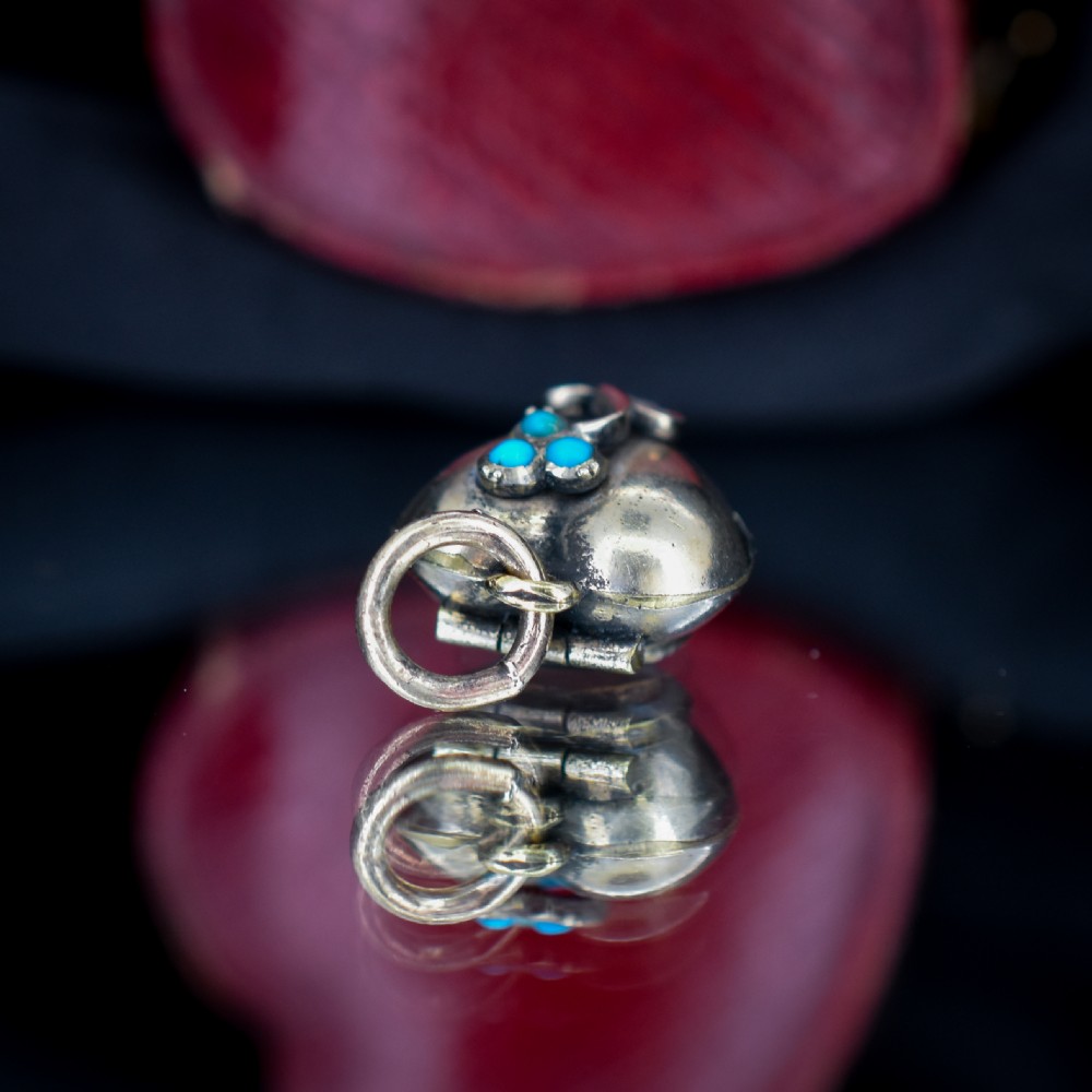 A heart-shaped gold pendant decorated with a raised stem motif set with three round blue turquoise cabochons in a floral pattern. View VII